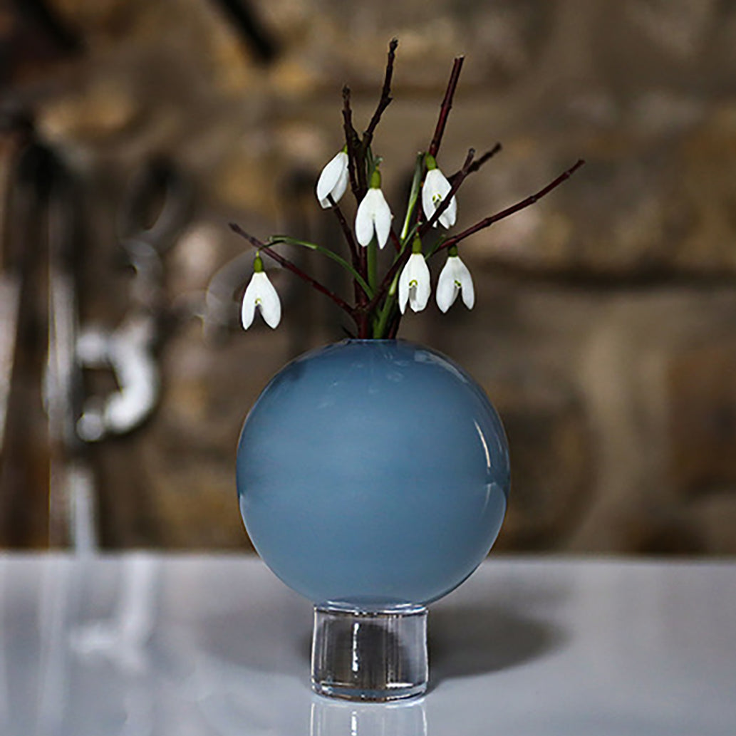 a round grey glass vase with snow drops and silver birch twigs