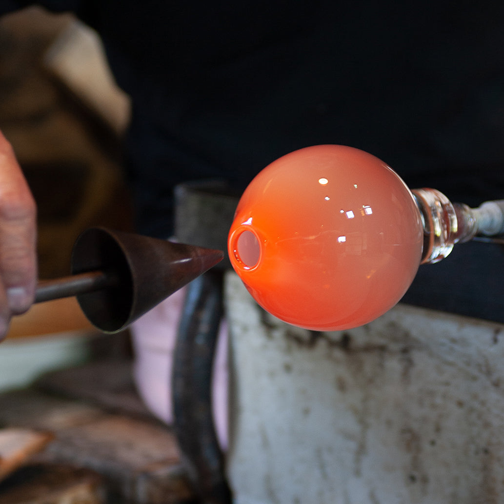 hot glass showing the process of making a round hand blown glass vase
